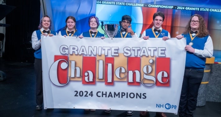Winning team from Merrimack holding Granite State Challenge 2024 Champions banner.