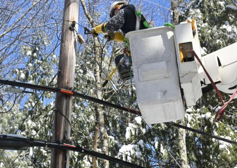 Lineworker in bucket works on wires attached to utility pole
