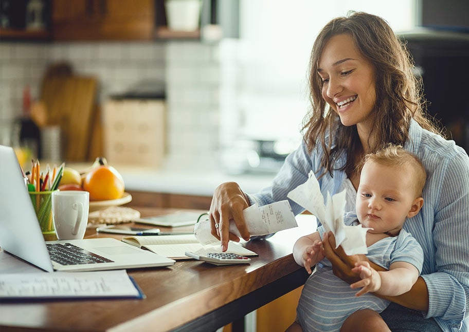 woman paying bills at home with baby on lap