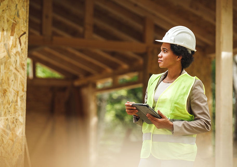 female contractor holding tablet and surveying new building frame