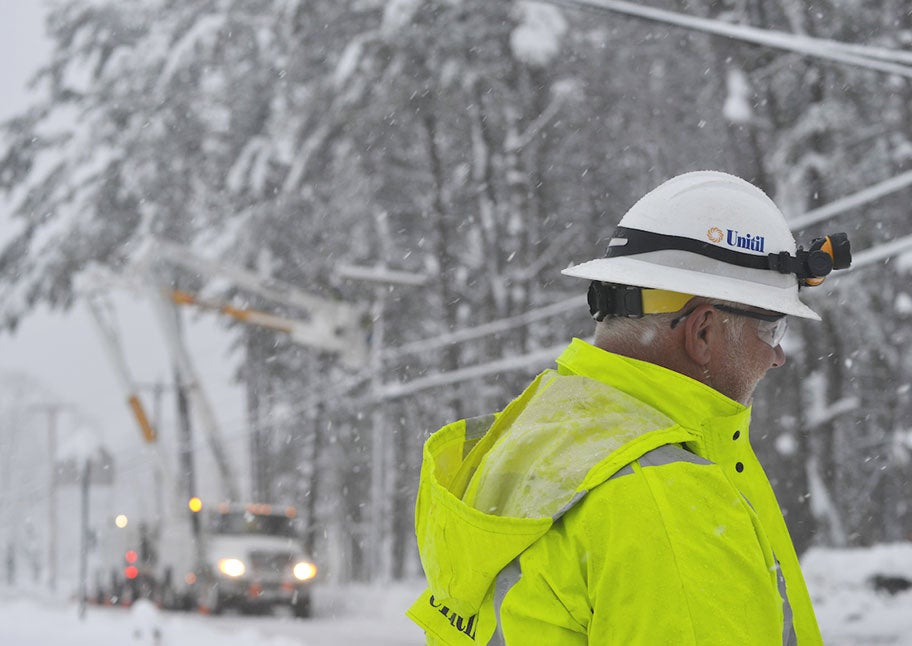 Unitil line worker in foreground of snow storm restoration