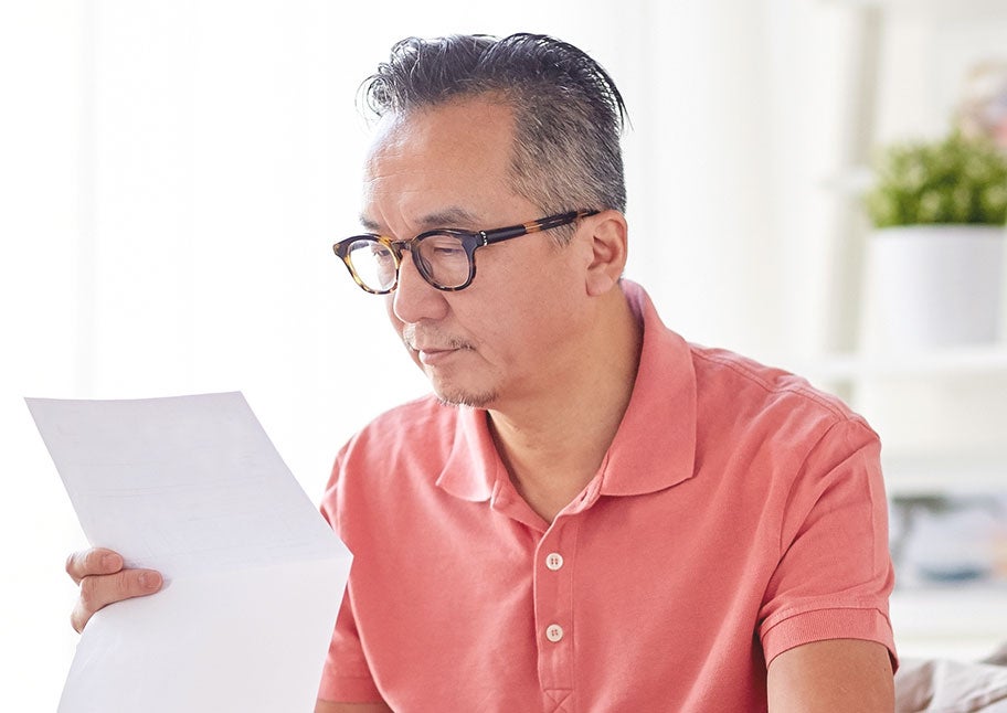 man looking at piece of paper at home