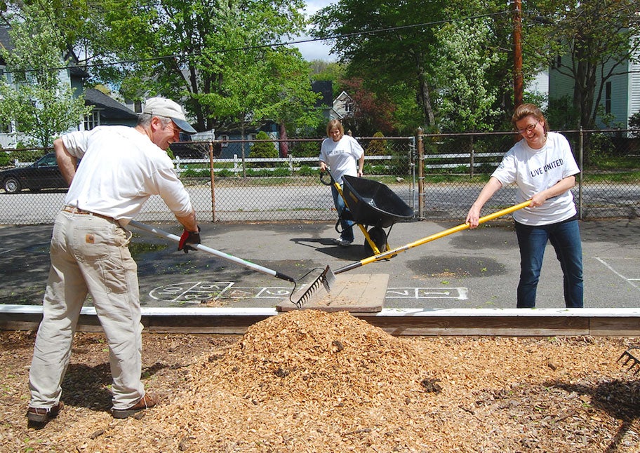 Unitil employees raking mulch on playground for United Way Day of Caring