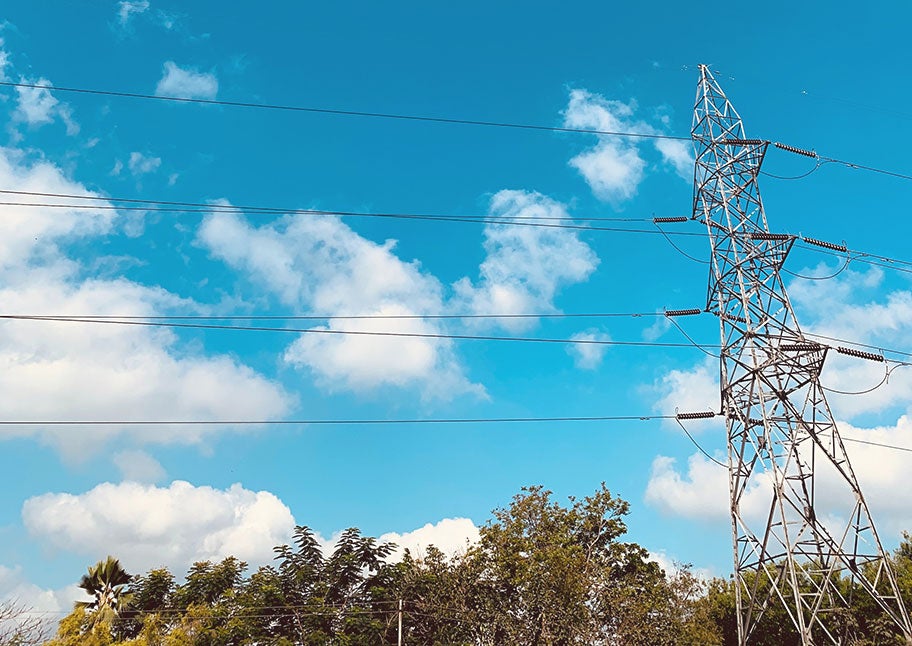 transmission line against tree line and blue sky