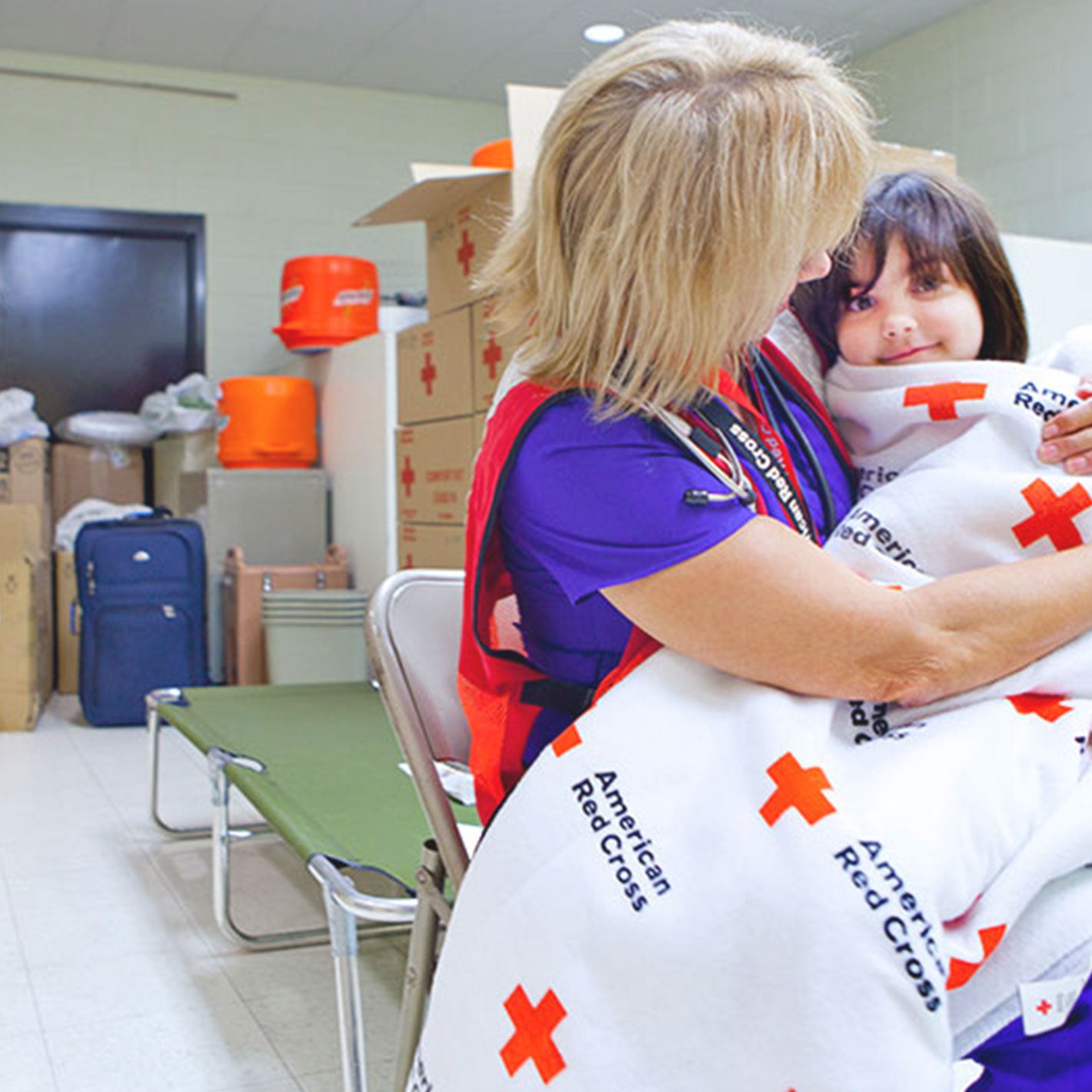 Red Cross volunteer holding little girl on lap