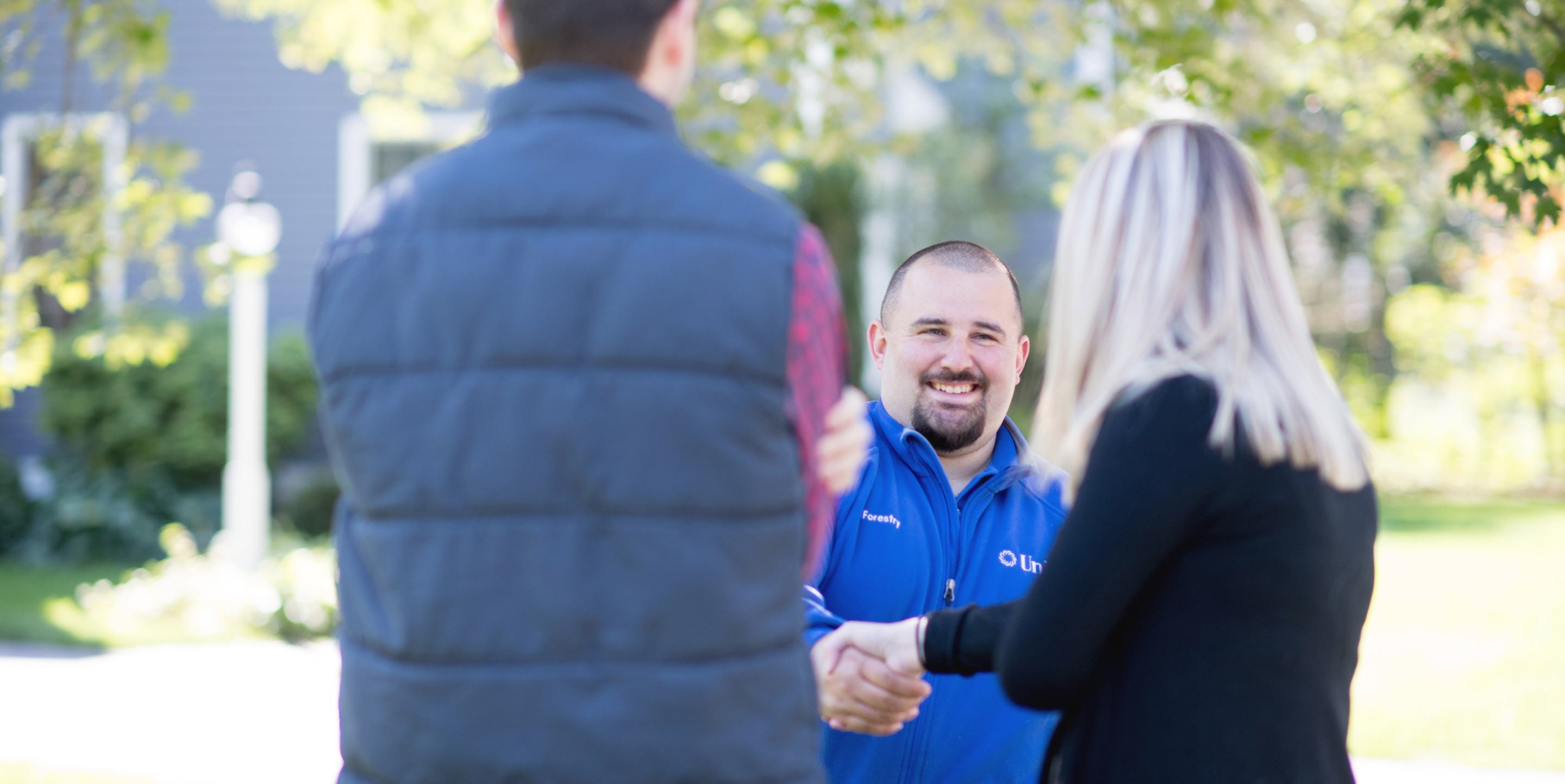 Unitil employee shaking hands with customers in yard