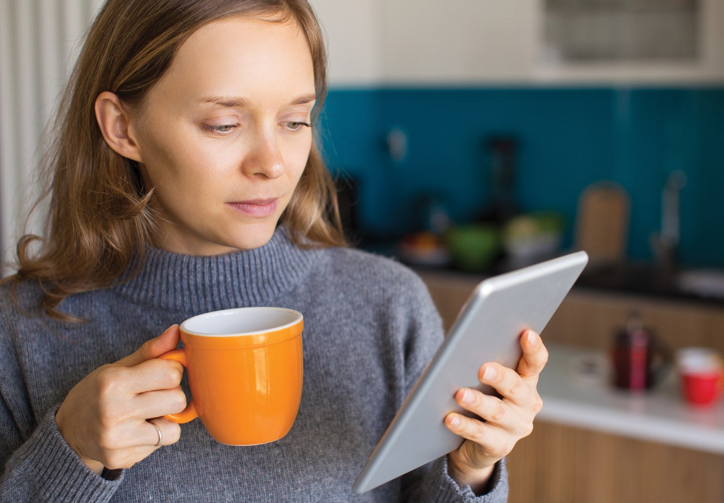 woman with coffee mug and tablet in kitchen