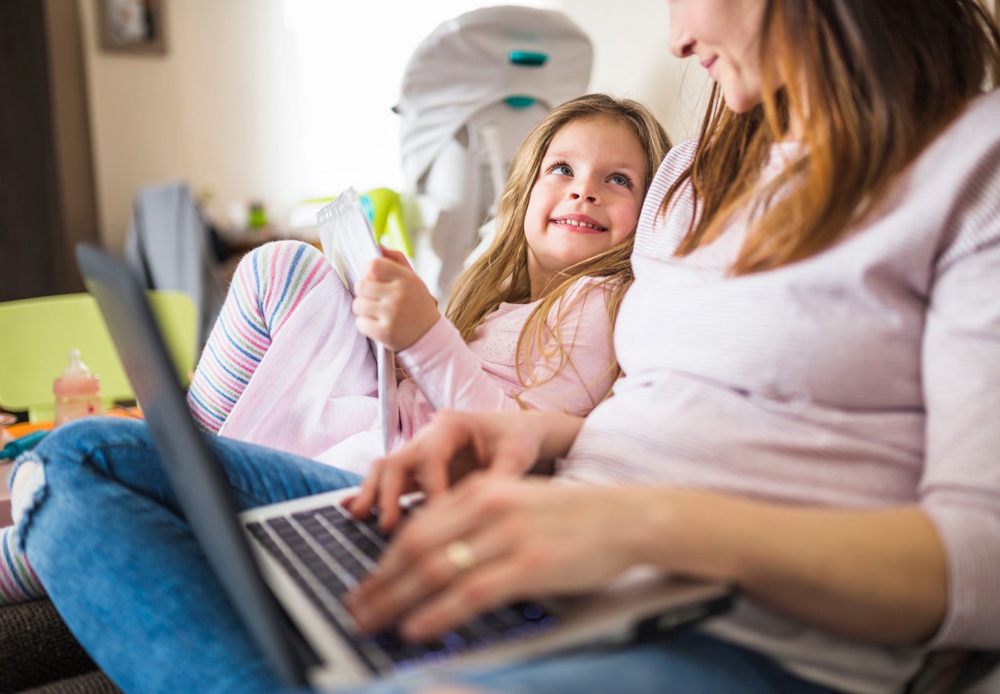 girl smiling up at her mother using a laptop