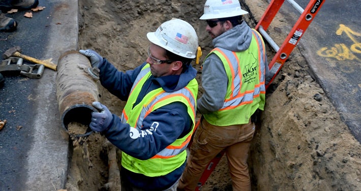 Workers from NEUCO remove the last section of cast iron pipe in Portland 