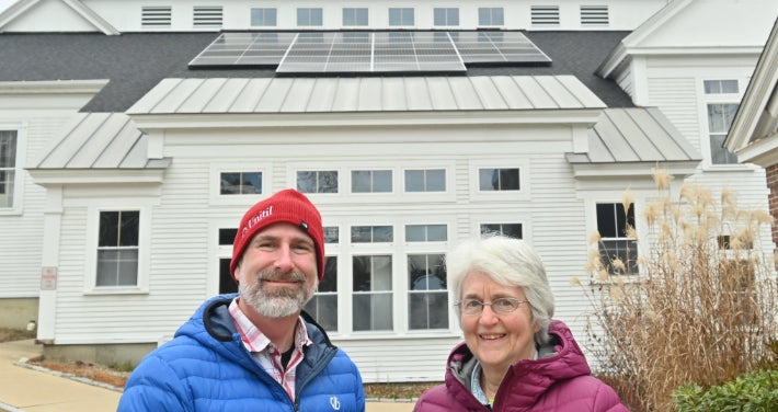 Church with solar panels in the background and two people in the foreground