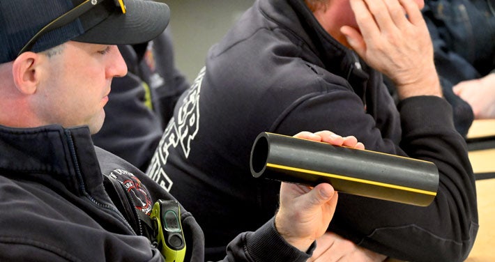 Emergency responder inspecting plastic gas pipe in classroom