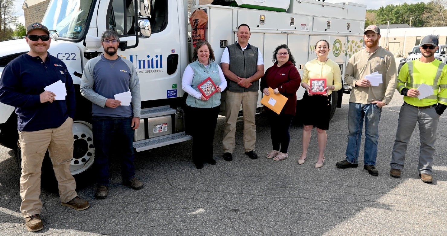 Unitil employees stand in front of a hybrid utility truck