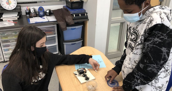 students in a classroom working with battery technology to produce electricity