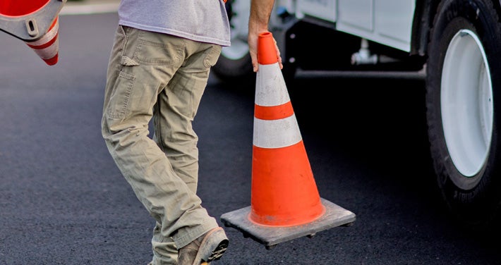 A Unitil employee places safety cones around a work site.