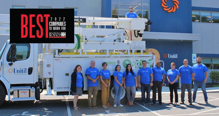 Unitil workers stand in front of hybrid truck at entrance of Unitil's Exeter facility