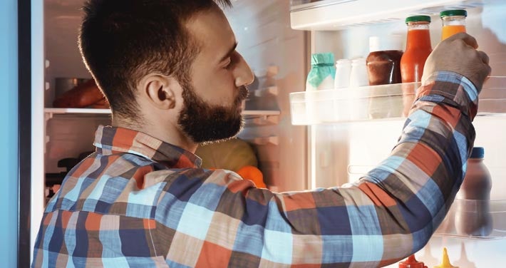 man with plaid shirt looking for food in refrigerator