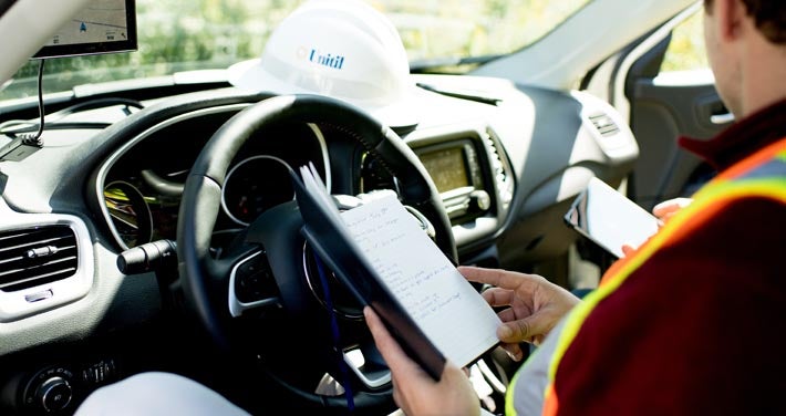 interior of Unitil truck with worker in driver's seat reviewing notebook