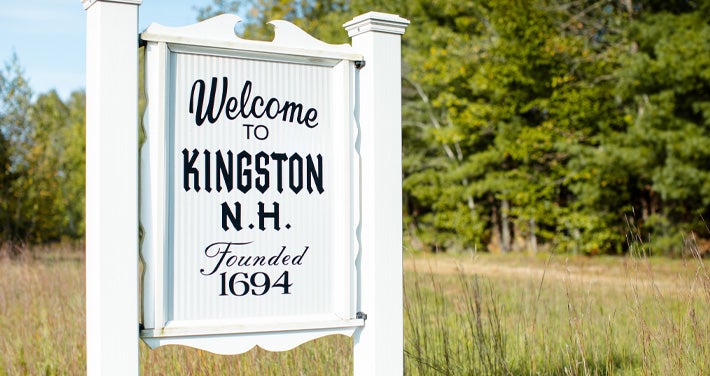 Kingston, NH, town sign with trees and grass in background