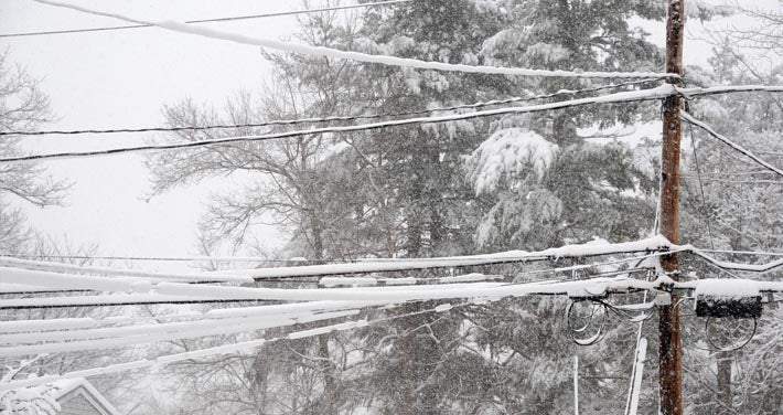 utility wires covered in snow with snow covered trees in background