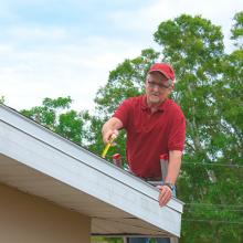 man working on roof of house with power lines in background