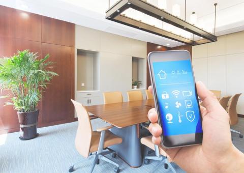hand in office holding phone with smart office app on screen