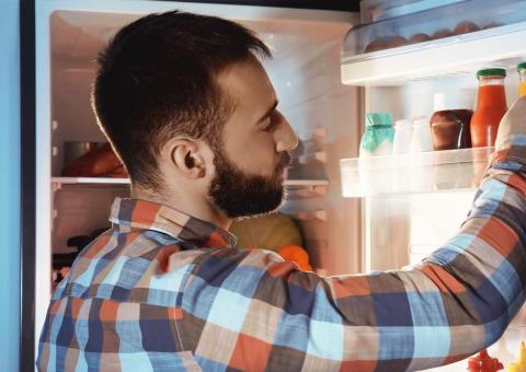 man with plaid shirt looking for food in refrigerator