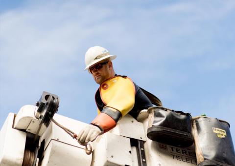 closeup view on Unitil line worker in bucket with sky background