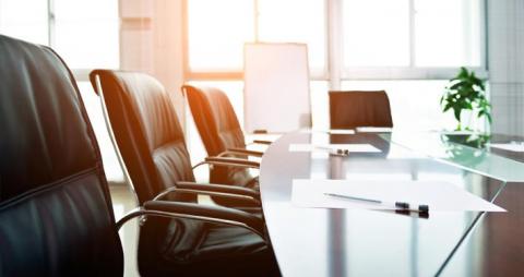 empty seats at a board room table with sun shining in