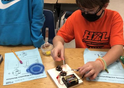 students in a classroom working with battery technology to produce electricity