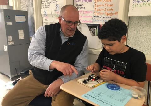 Unitil consultant helps student who is work on a circuit board 