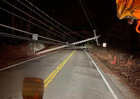 fallen tree covers street with downed wires at night
