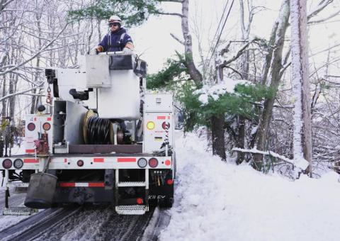 Unitil worker in bucket truck on side of snowy road