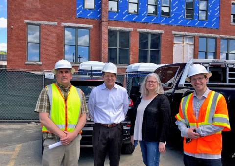 workers pose on street in front of Moran Square building construction