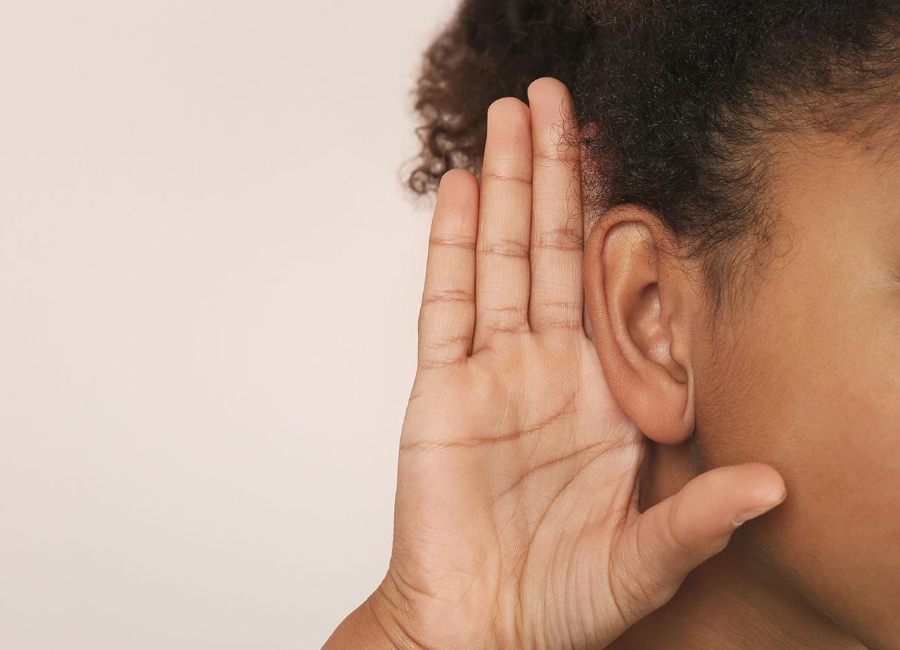 close up of girl listening with hand on ear